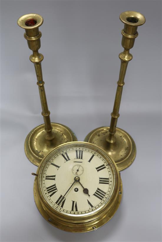 A brass bulkhead clock by Sewell, Maker to the Admiralty, Liverpool and a pair of tall brass slender candlesticks clock dia 26cm